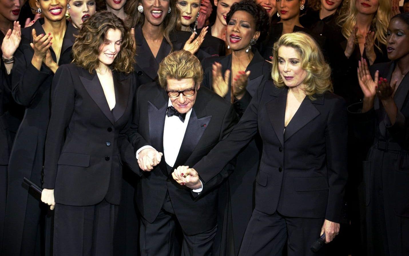 Yves Saint Laurent 2002 med Laetitia Casta och Catherine Deneuve efter sin sista visning. Han är bland annat känd för att ha klätt kvinnor i eleganta byxdressar.