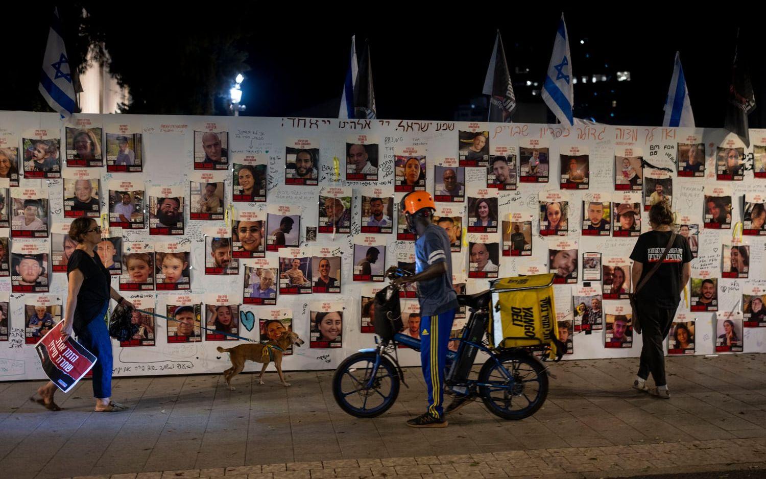 Förbipasserande vid en minnesvägg i Tel Aviv för de över 220 personer som togs som gisslan av Hamas den 7 oktober.