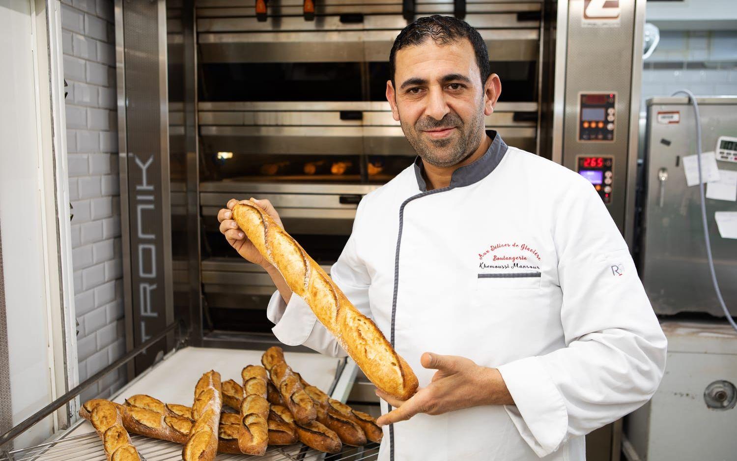 Bagaren visar upp en traditionelle baguette. Den är något gråaktig inuti, till skillnad från den klassiska baguetten som är vit.