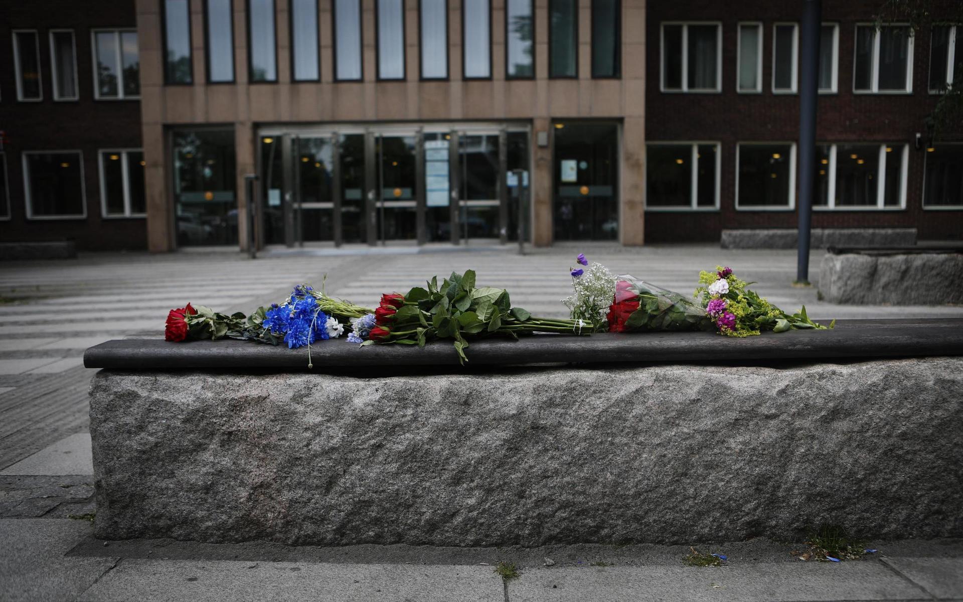 Flagga på halv stång och blommor utanför polishuset.