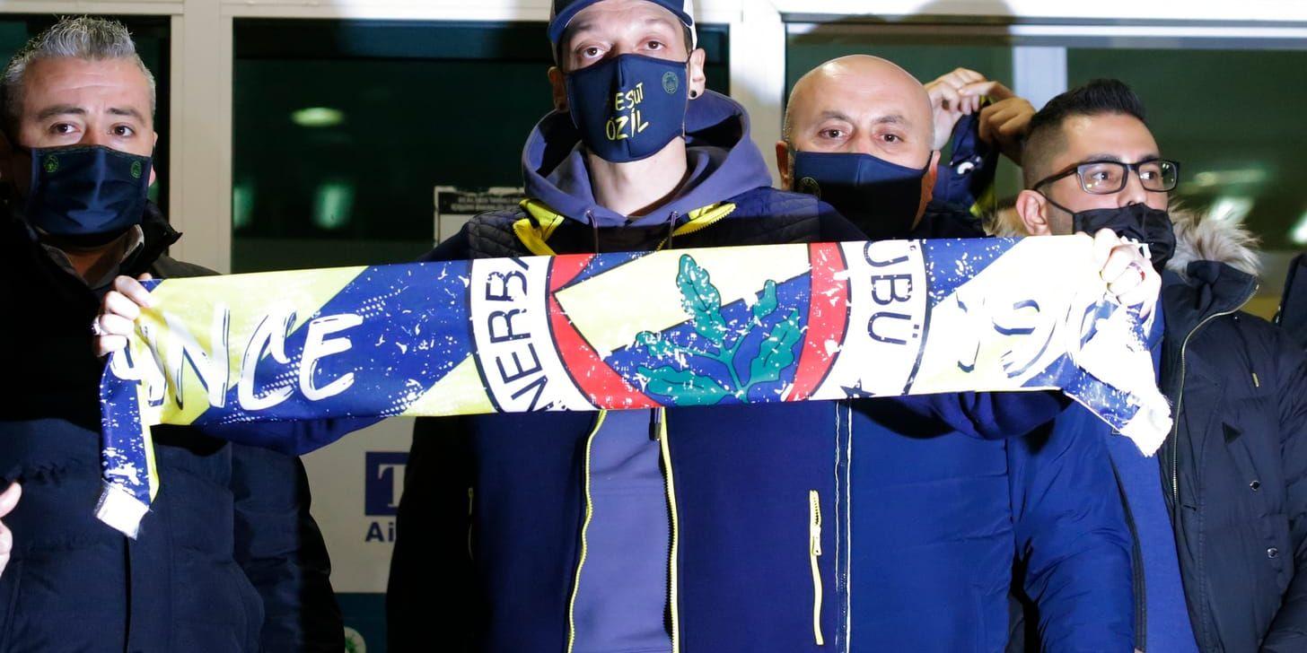 Mesut Özil poserar med en Fenerbahcehalsduk på flygplatsen i Istanbul.