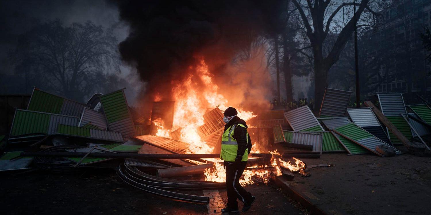 En demonstrant vid Triumfbågen på Champs-Elysees. Nu stoppas flera av helgens franska ligamatcher på grund av oroligheterna. Arkivbild.