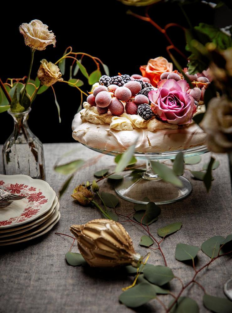 Marängtårta på ett tårtfat. Vacker dukning, blommor och blad.