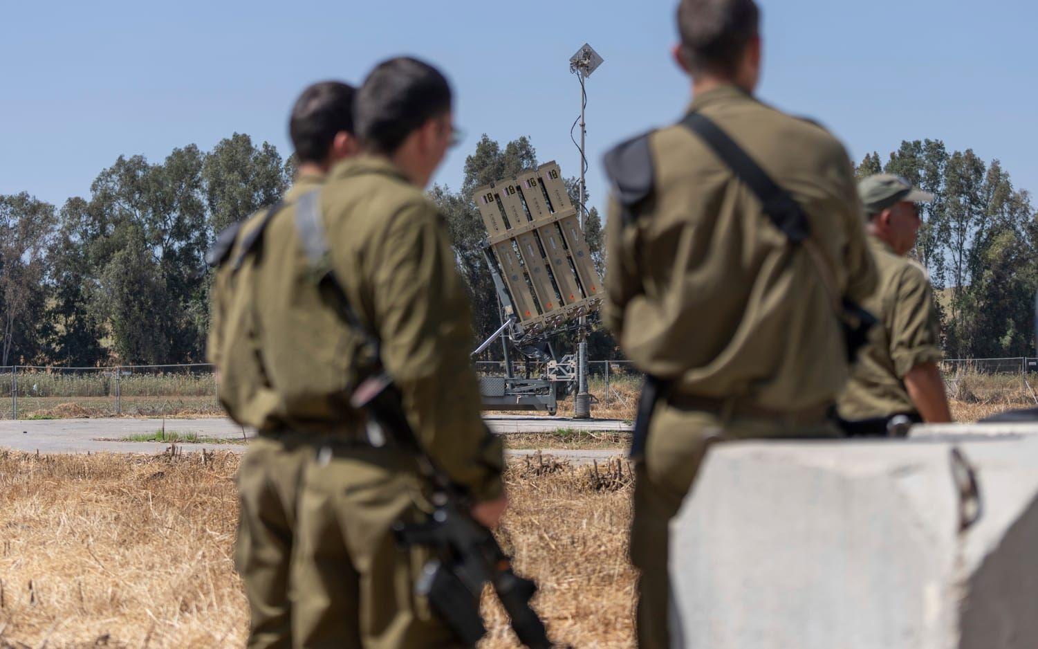 Israeliska soldater med en del av landets Iron dome-försvar i bakgrunden. 