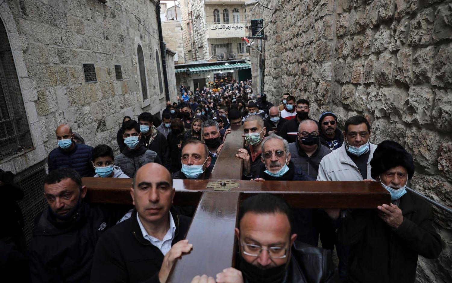 Kristna bär ett kors längs Via Dolorosa i Jerusalem. 