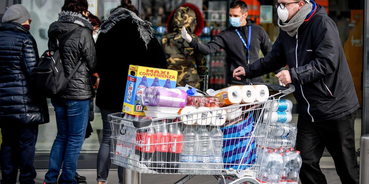 Människor med munskydd köar för att köpa på sig förnödenheter inför vad som kan bli flera veckors isolering, i orten Casalpusterlengo.