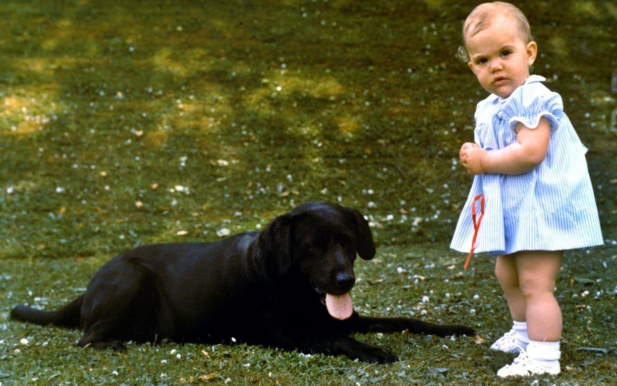 På ettårsdagen fångade pappa kungen sin dotters första födelsedag på bild. Här är den lilla prinsessan på Solliden med familjens labrador Charlie. 